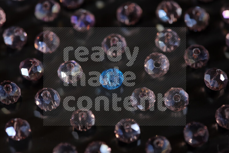 Rose and blue transparent crystal beads scattered on a black background
