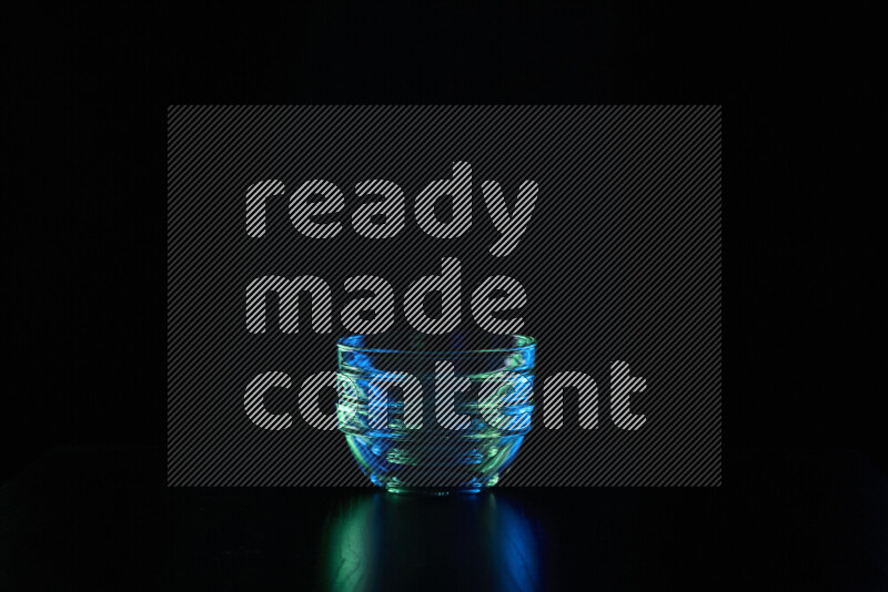 Glassware with rim light in blue and green against black background