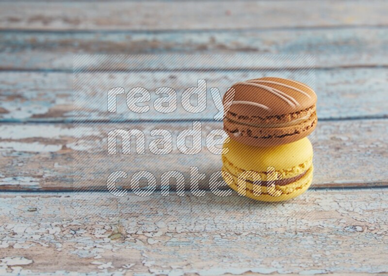 45º Shot of of two assorted Brown Irish Cream, and Yellow Lemon macarons on light blue background