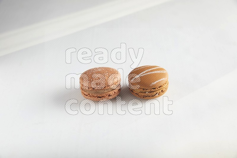 45º Shot of of two assorted Brown Irish Cream, and Brown Hazelnuts macarons on white background