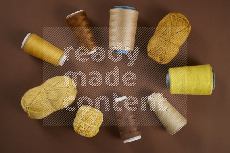 A yellow collection of sewing and tailoring tools arranged on a brown background