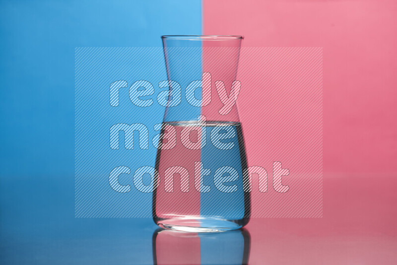 The image features a clear glassware filled with water, set against blue and pink background