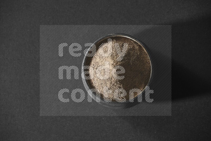 بودرة الفلفل الأسود في وعاء فخاري أسود علي خلفية سوداء