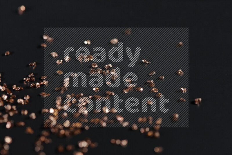 Bronze shimmering fragments of glass scattered on a black background