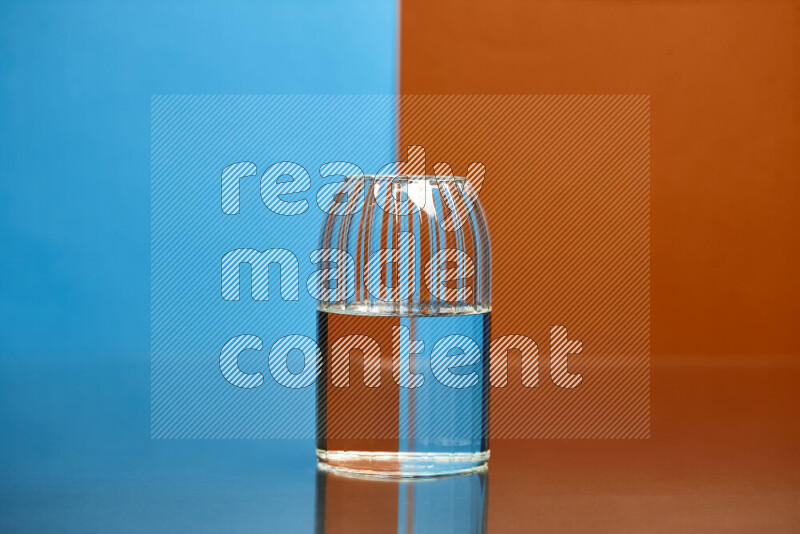 The image features a clear glassware filled with water, set against blue and dark orange background