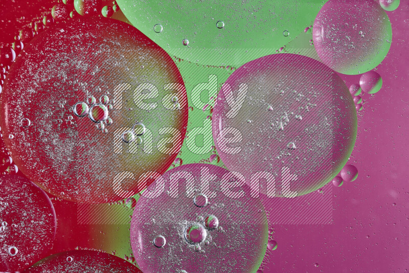 Close-ups of abstract oil bubbles on water surface in shades of pink, green and red