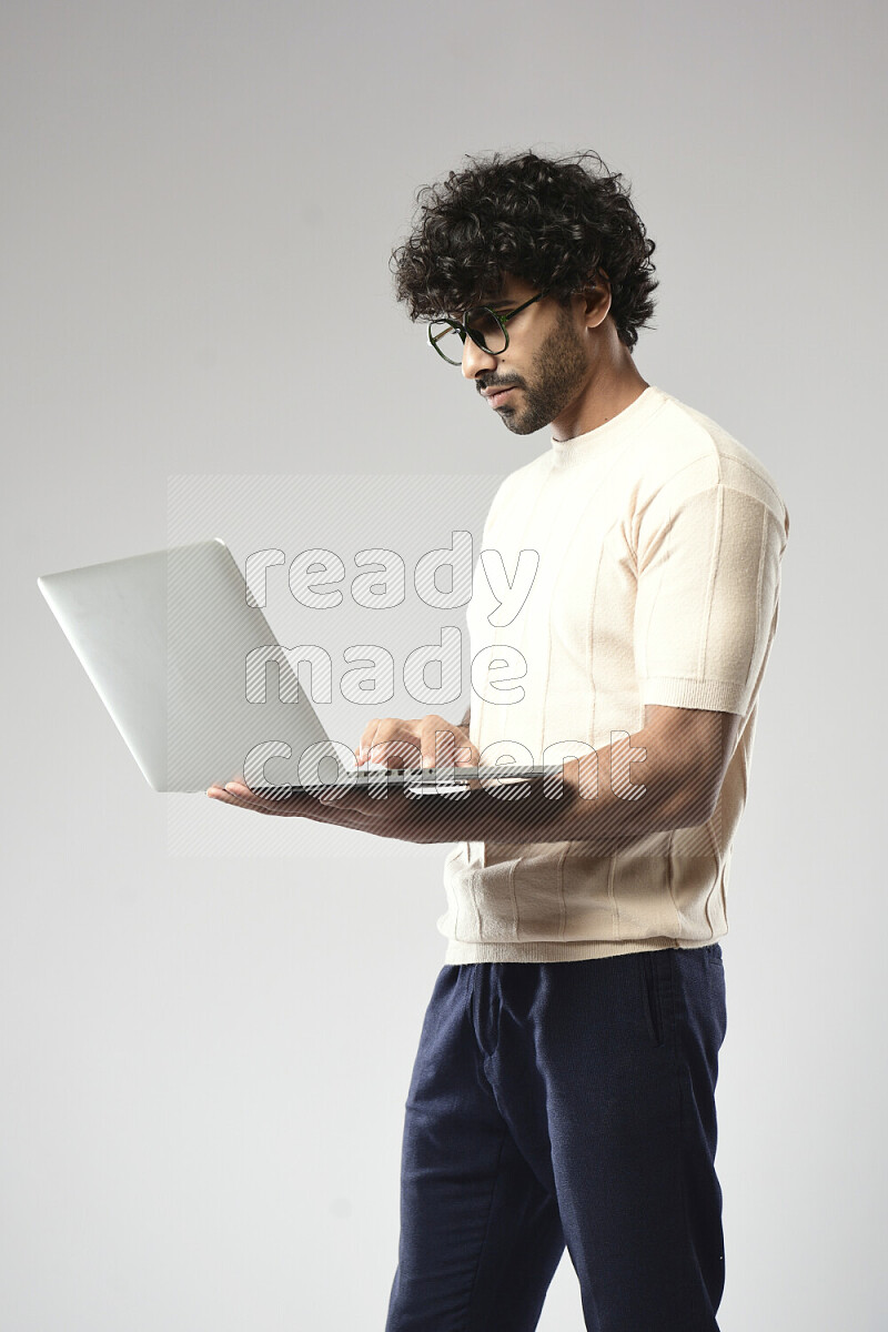 A man wearing casual standing and working on a laptop on white background