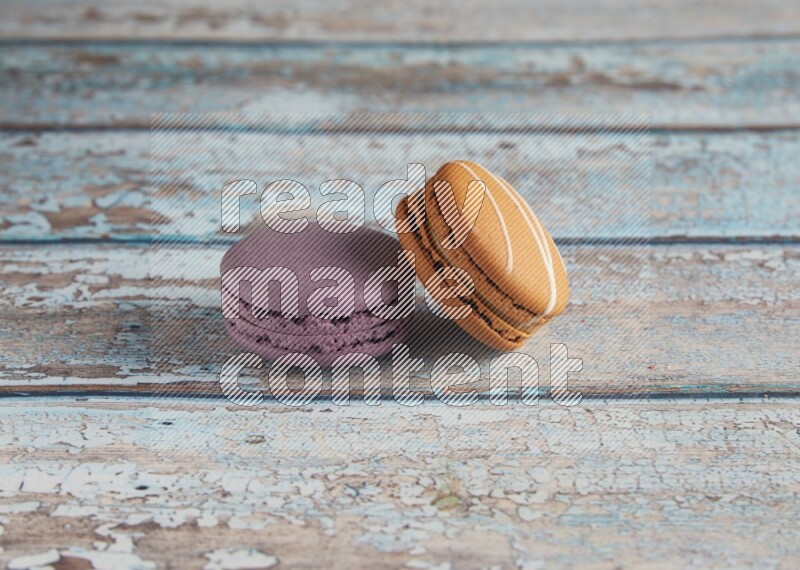 45º Shot of of two assorted Brown Irish Cream, and Purple Blueberry macarons  on light blue background