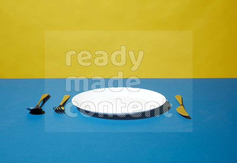 white plate and silverware on yellow and blue background