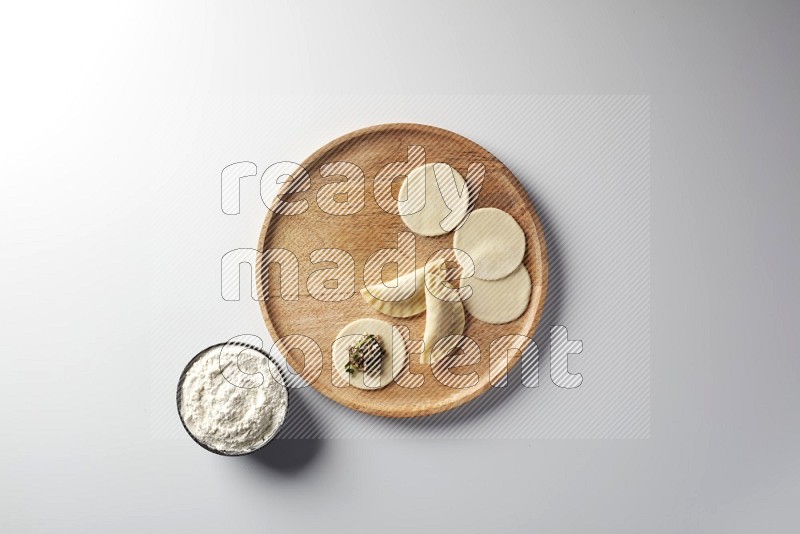 two closed sambosas and one open sambosa filled with meat while flour aside in a wooden dish on a white background