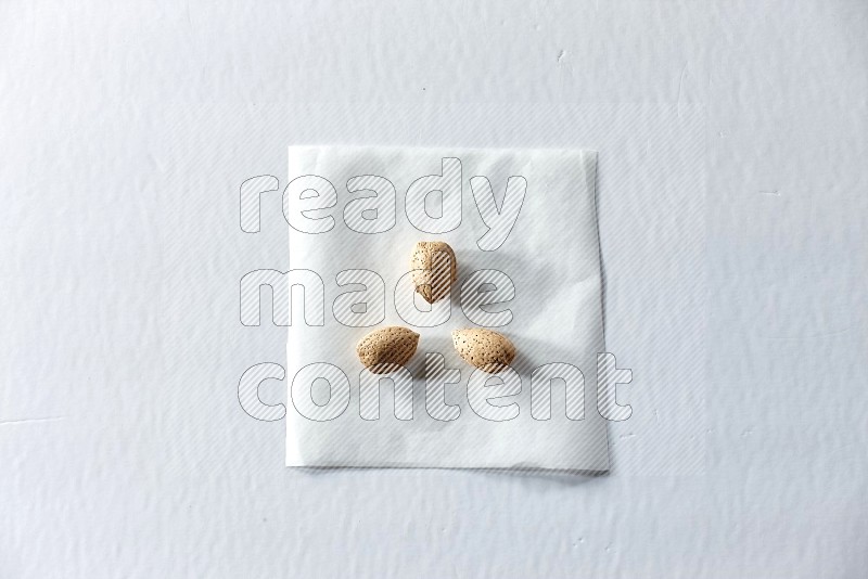 3 almonds on a piece of paper on a white background in different angles