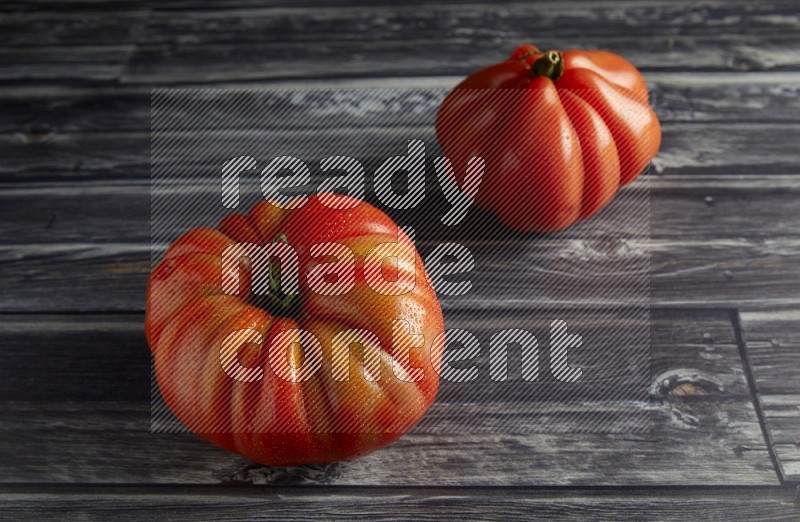 45 degree two heirloom tomato on a textured grey wooden background