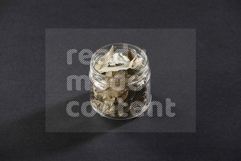 A glass jar filled with laurel bay on black flooring in different angles
