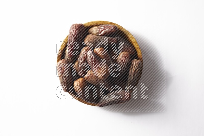 Dates in a wooden bowl on white background