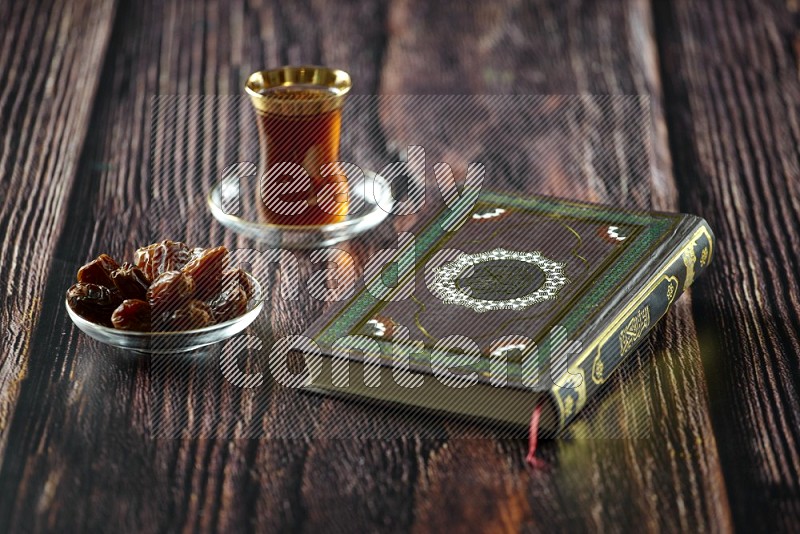 Quran with dates, prayer beads and different drinks all placed on wooden background