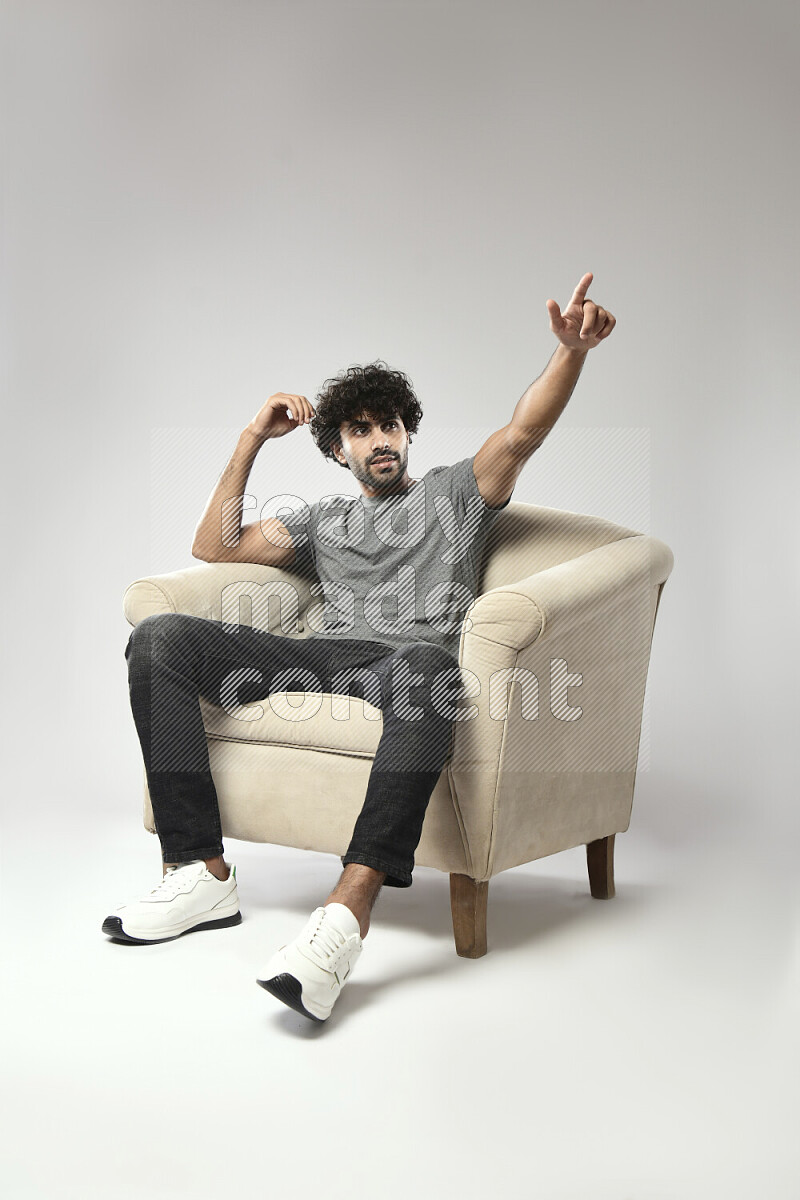 A man wearing casual sitting on a chair making a hand gesture on white background