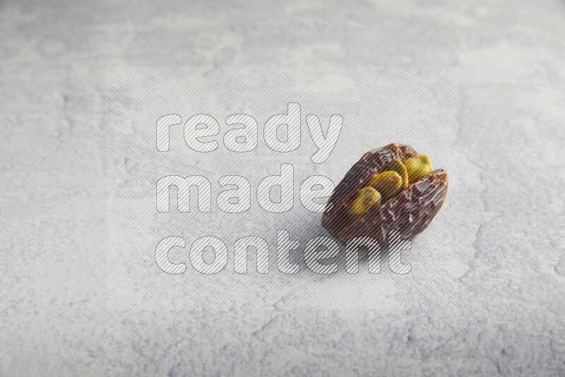 pistachio stuffed madjoul date on a light grey background