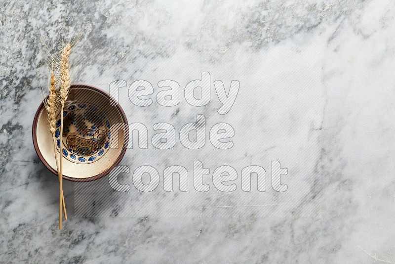 Wheat stalks on Decorative Pottery Plate on grey marble flooring, Top view