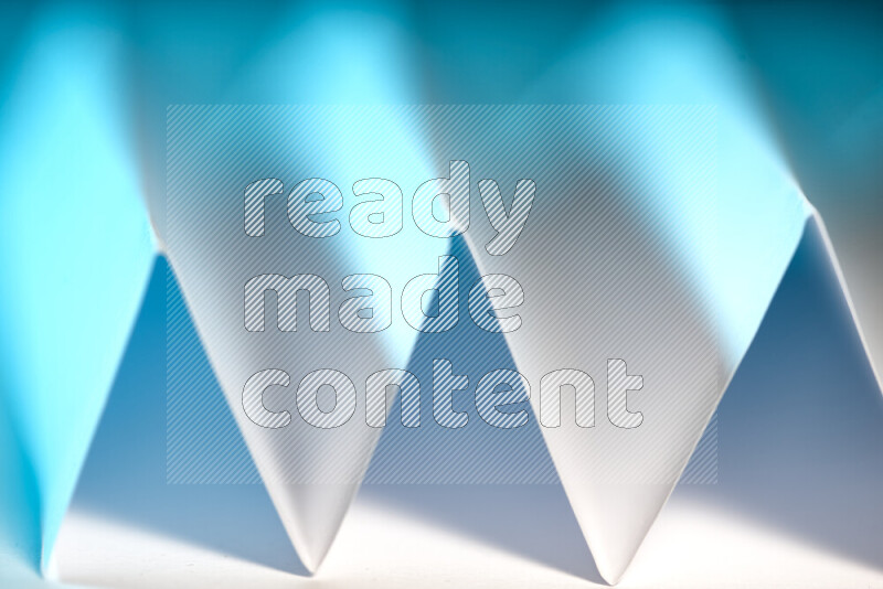 A close-up abstract image showing sharp geometric paper folds in white and blue gradients