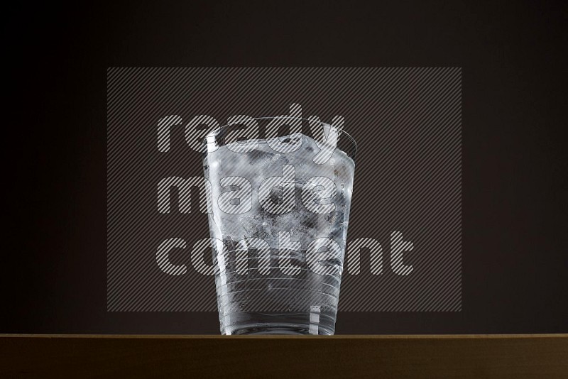 Low angle shot of a glass of water and ice on grey background