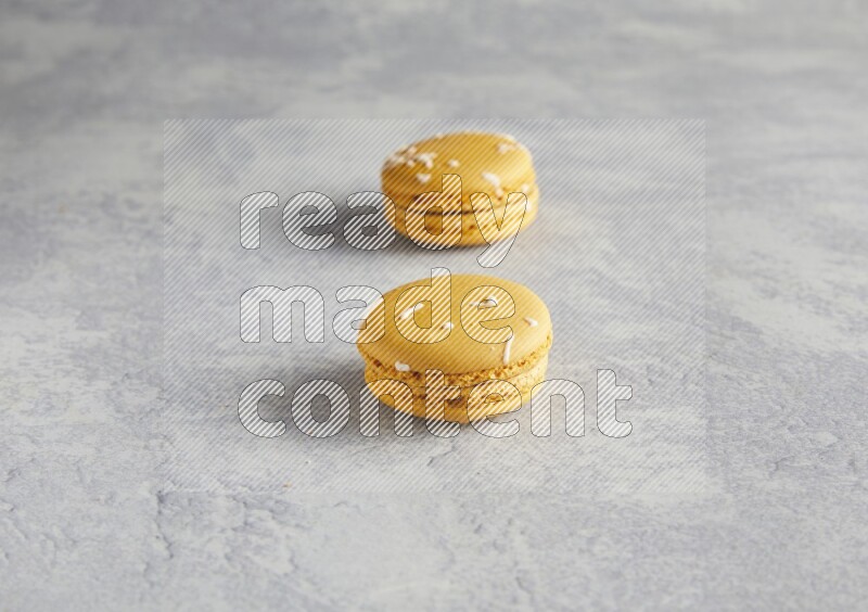45º Shot of two Yellow Piña Colada macarons  on white  marble background