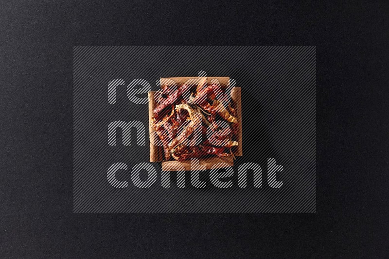 A single square of cinnamon sticks full of chilis on black flooring