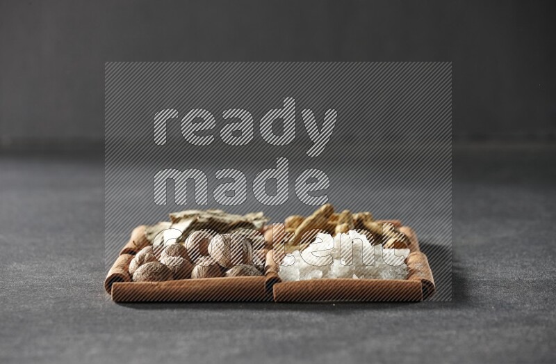 4 squares of cinnamon sticks full of bay laurel leaves, white salt, turmeric fingers and nutmegs on black flooring