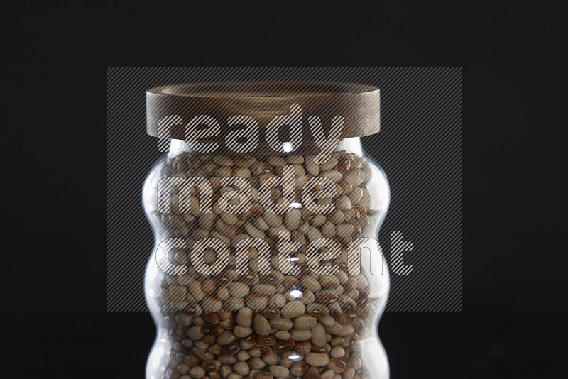 Black-eyed peas in a glass jar on black background