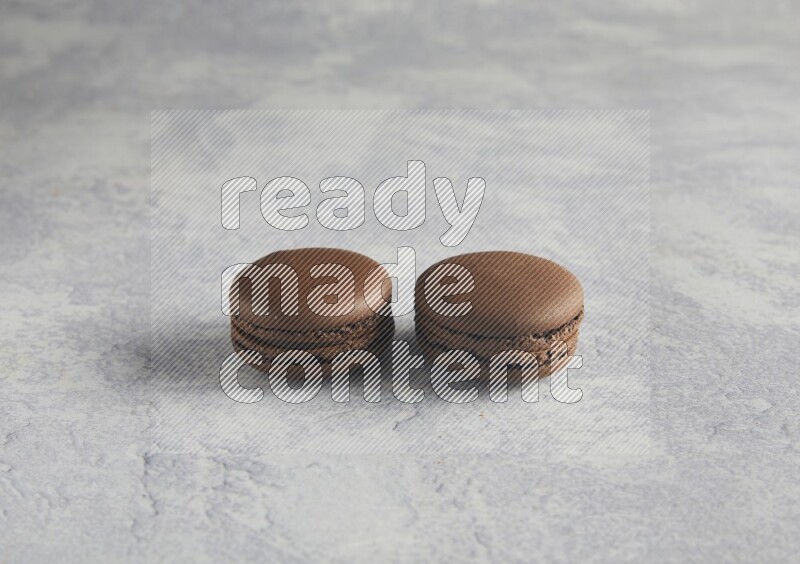 45º Shot of two Brown Dark Chocolate macarons  on white  marble background