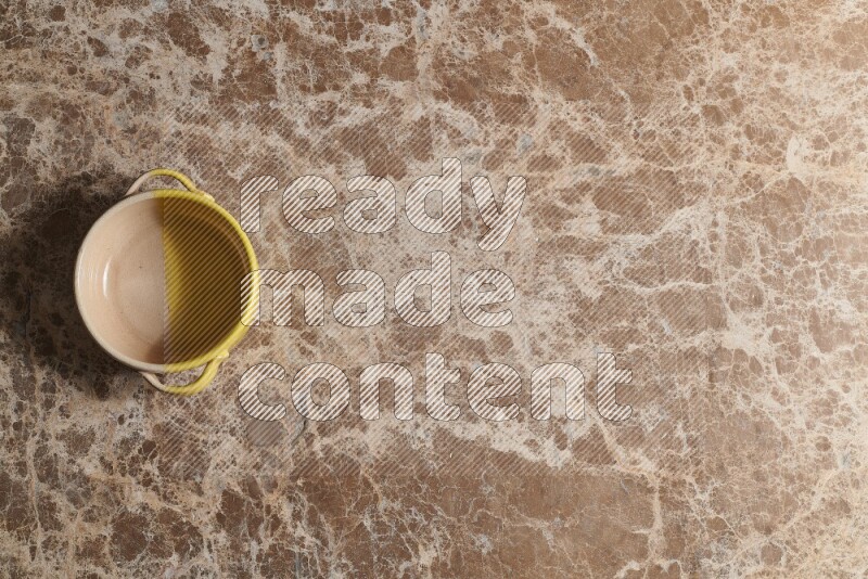 A multicolored pottery bowl on beige marble background