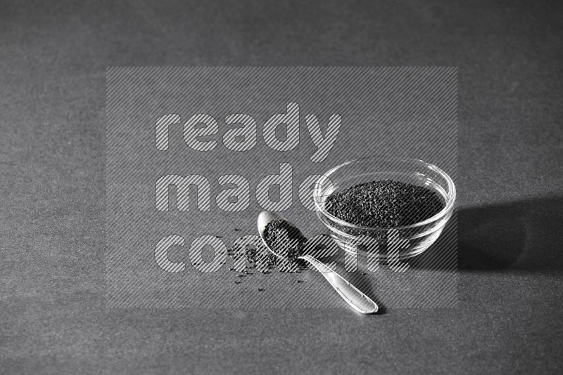 A glass bowl full of black seeds with a metal spoon full of the seeds on a black flooring in different angles