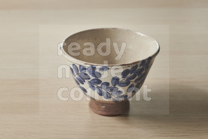 A decorative pottery bowl on light wooden background