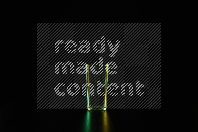 Glassware with rim light in green and yellow against black background