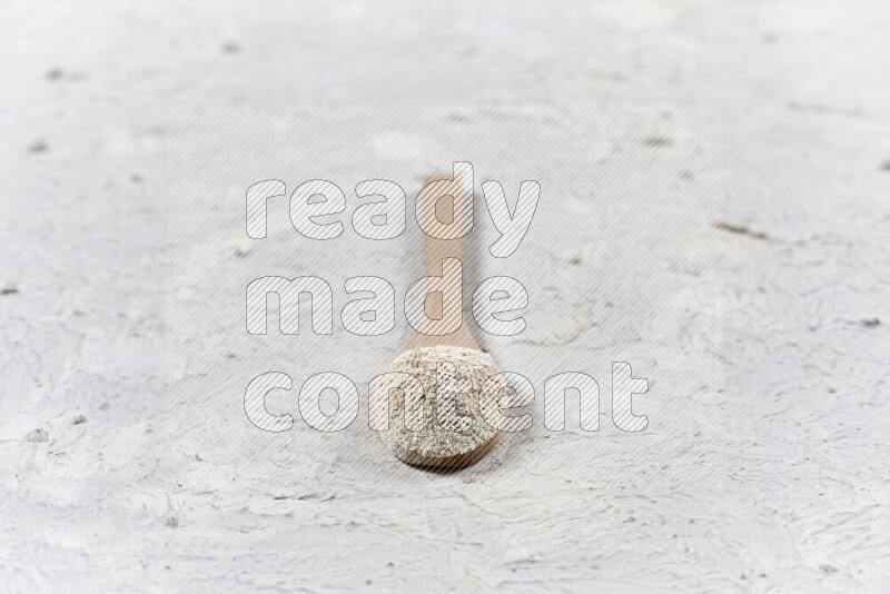 A wooden spoon full of onion powder on white background