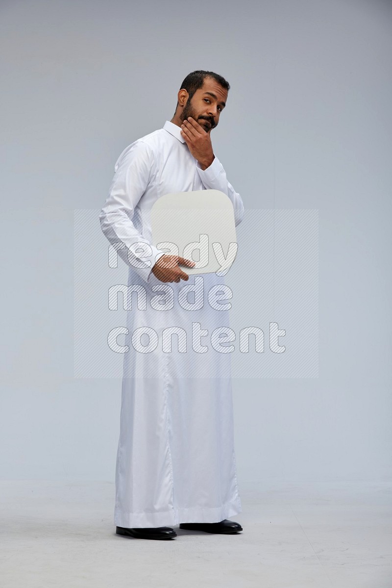 Saudi man wearing Thob standing holding social media sign on Gray background