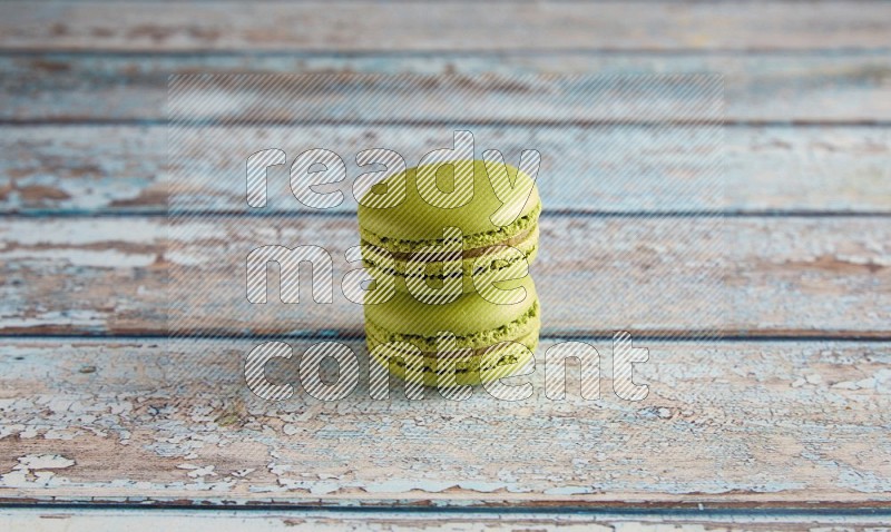 45º Shot of two Green Pistachio macarons on light blue wooden background