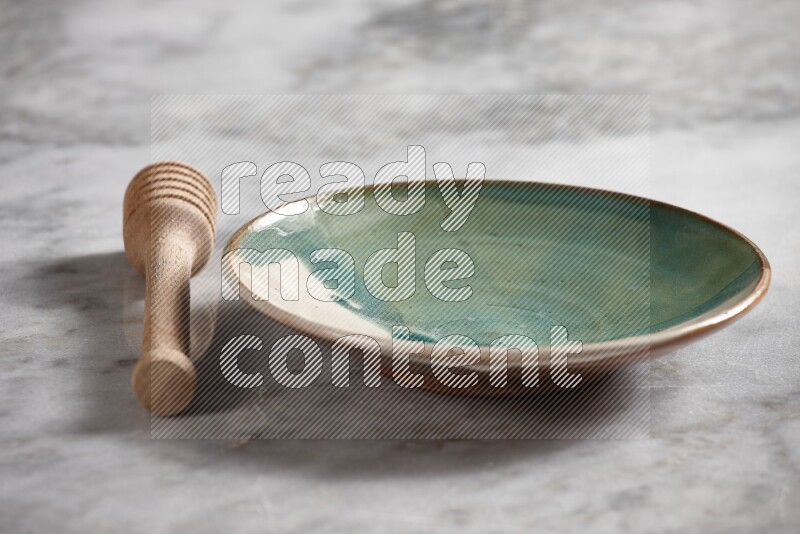 Multicolored pottery plate with wooden honey dipper on the side on grey marble background