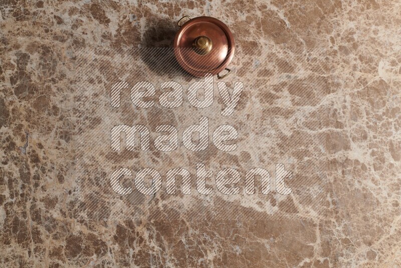 A small copper pot on beige marble background