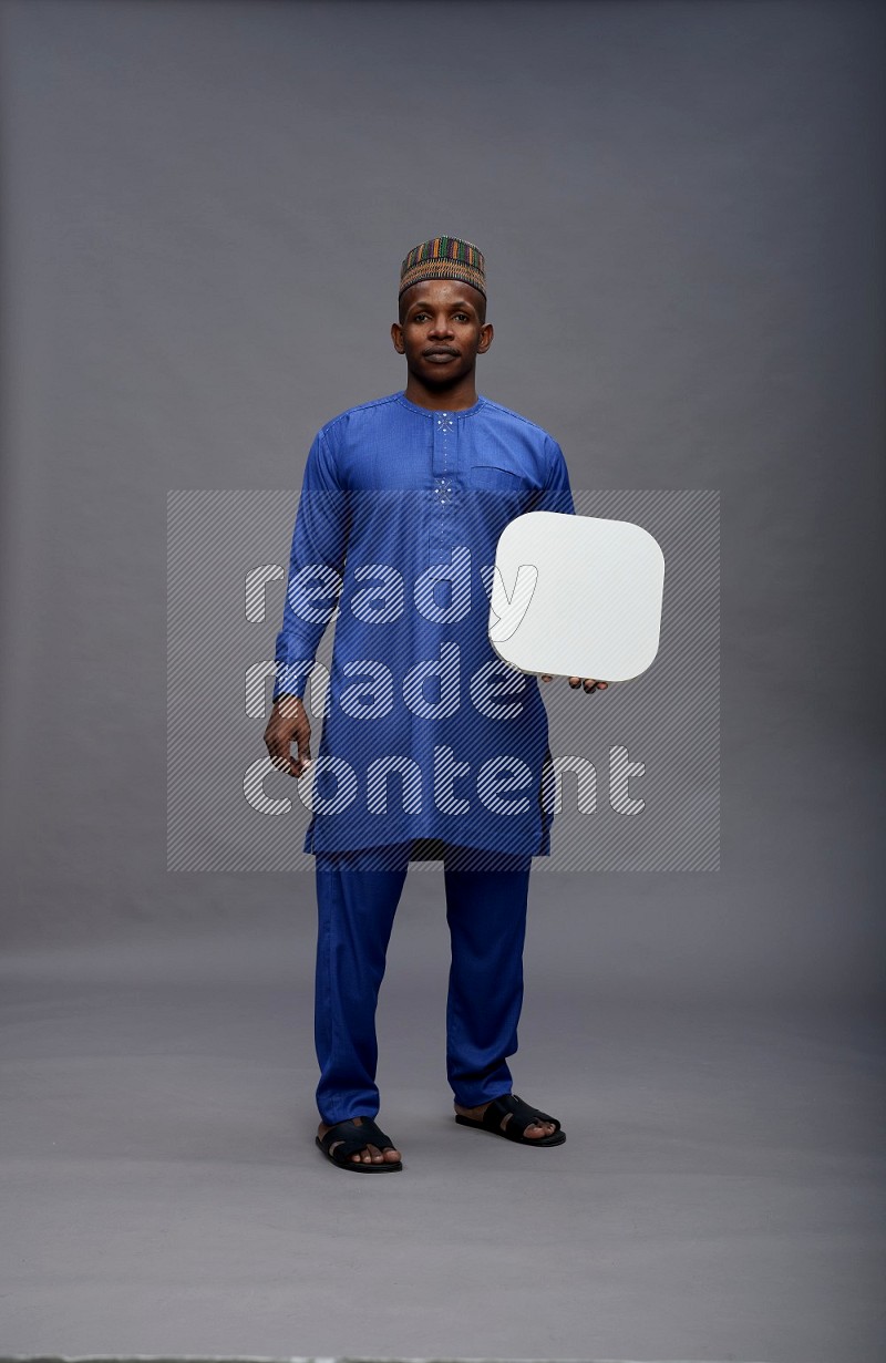 Man wearing Nigerian outfit standing holding social media sign on gray background