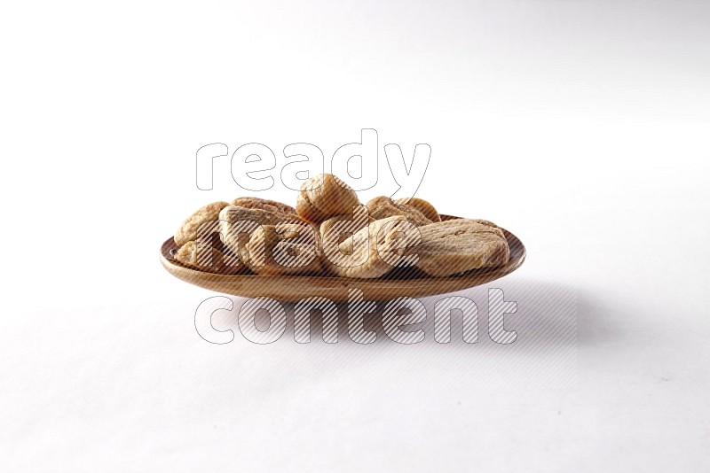 Dried figs in a wooden plate on white background