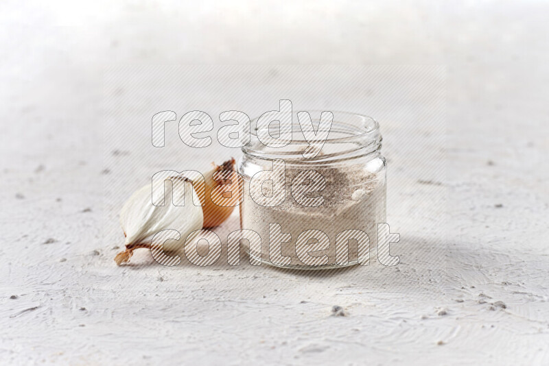 A glass jar full of onion powder on white background