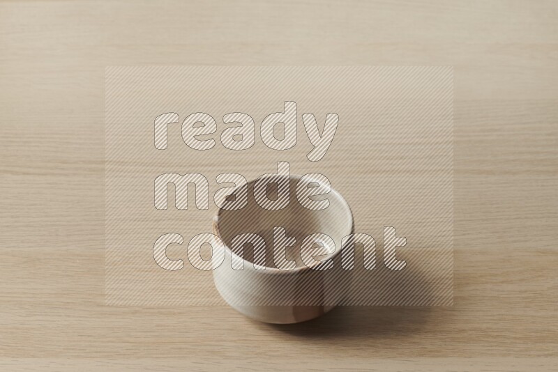 A beige pottery bowl on light wooden background