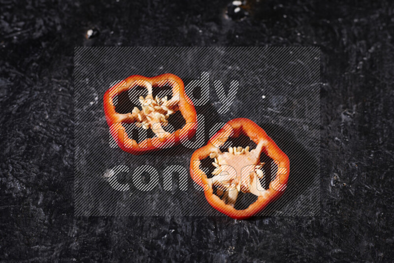 Red bell pepper slices on black background