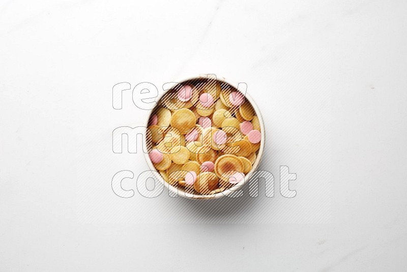 Top-view shot of pink chocolate chips cereal pancakes in a round bowl on white background