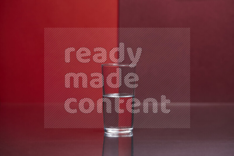 The image features a clear glassware filled with water, set against red and dark red background