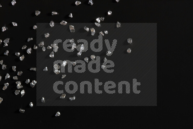 قطع زجاجية فضية لامعة متناثرة على خلفية سوداء