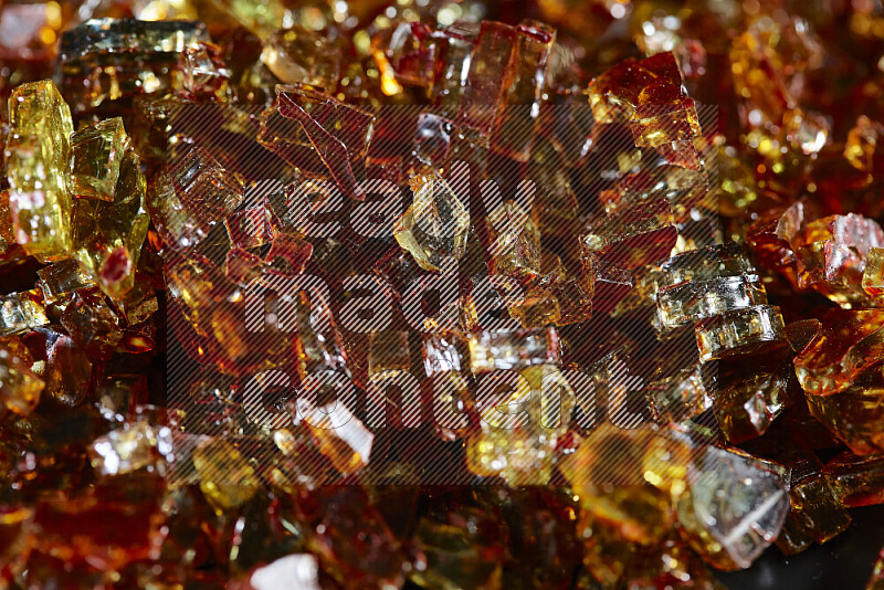 Transparent orange fragments of glass scattered on a black background