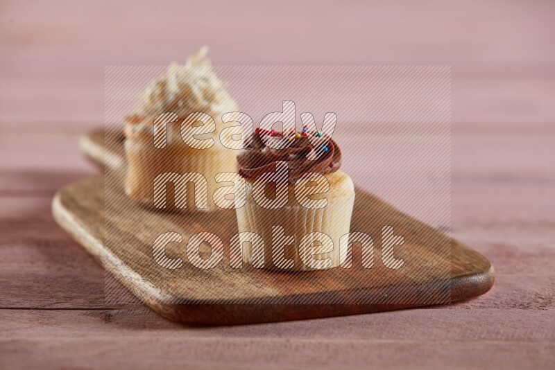 Vanilla mini cupcake topped with chocolate cream on a wooden board
