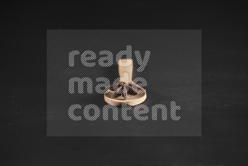 Star Anise in a wooden spoon on more stars anise filling the frame on black flooring