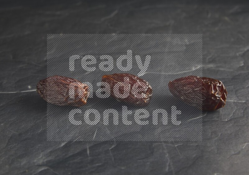 three madjoul dates on a black textured background